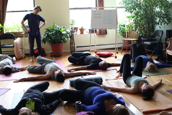 Teacher observes 500 hr-teacher training students learning breath-based yoga 